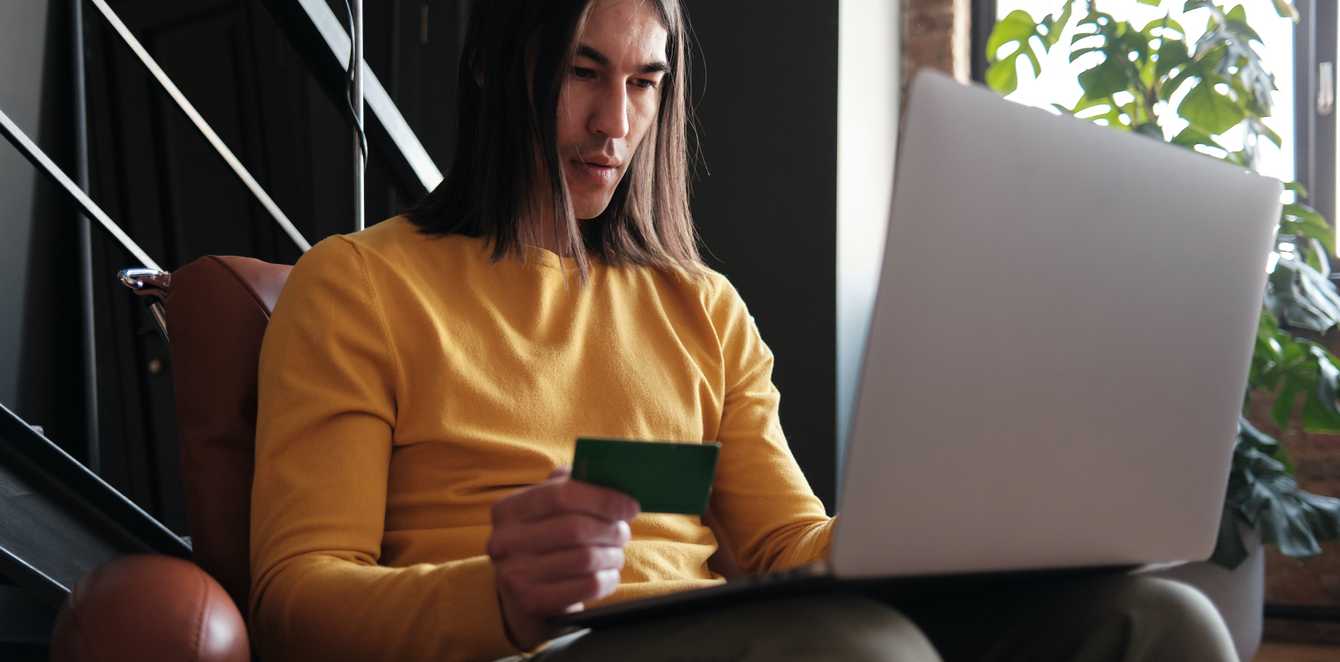 Person on a laptop holding a credit card