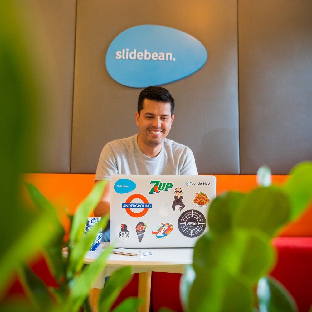 Man in a colorful office sitting behind a laptop covered with stickers
