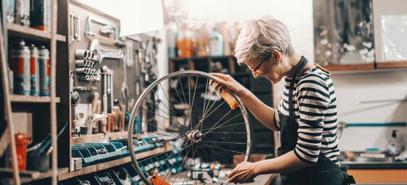 Worker holding and repairing bicycle wheel while standing in
workshop.
