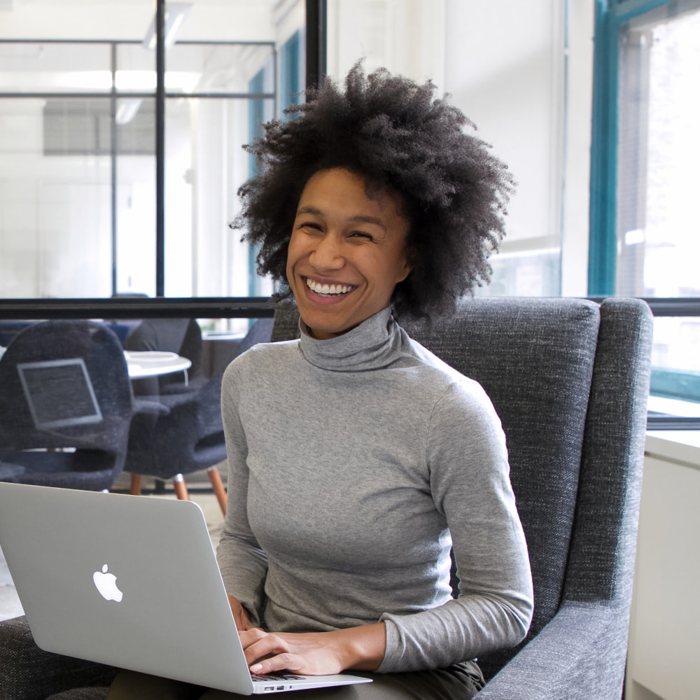 Persona inteligente sonriendo a la cámara con una laptop en el regazo