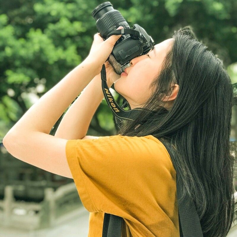 Woman holding a camera to her eye and pointing it towards the sky