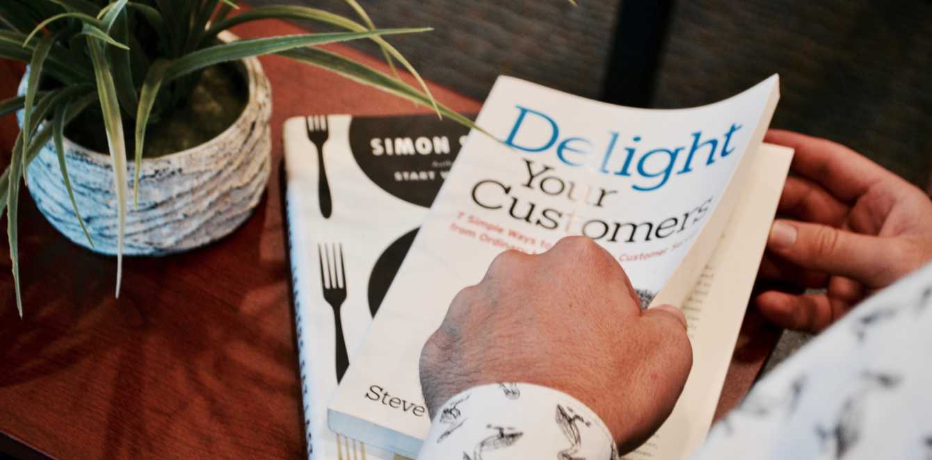 Person holding Delight your Customer book