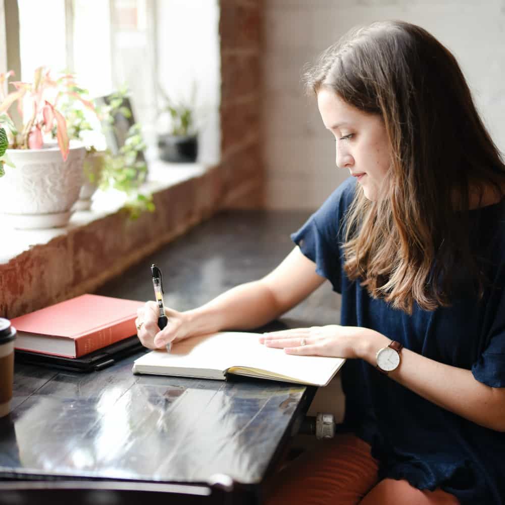 Woman sitting at a desk writing in a notebook